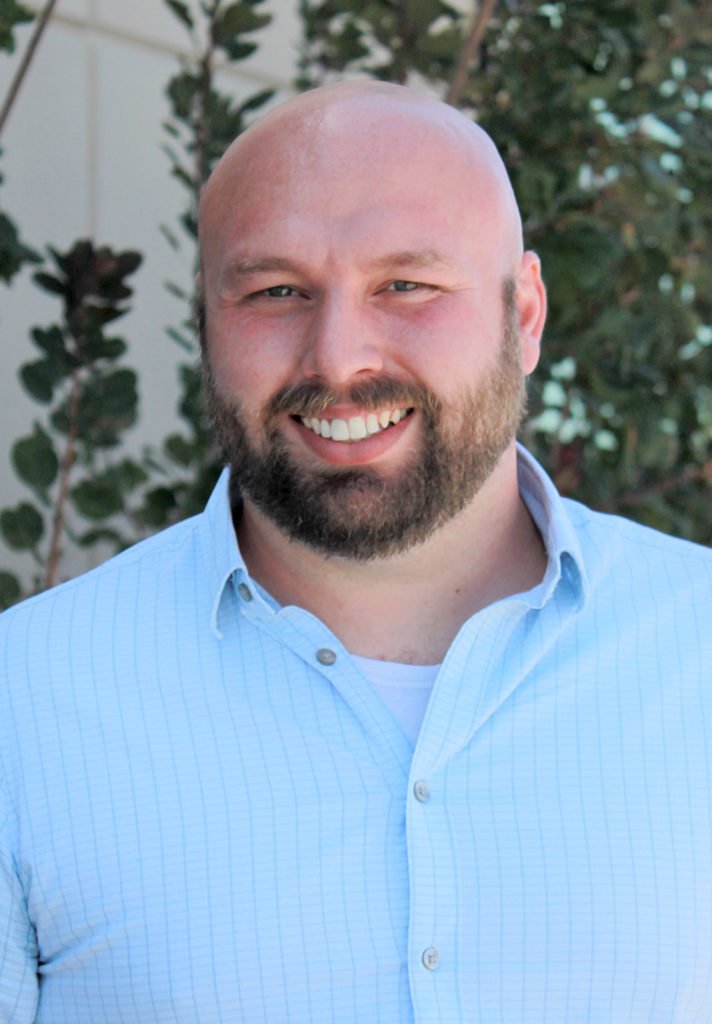 A smiling man, Jacob Szeszulski, in an outdoor setting