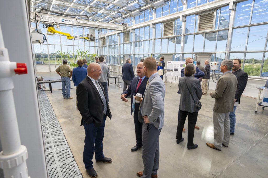 Many people are looking around and talking inside the Plant Growth and Phenotyping Facility
