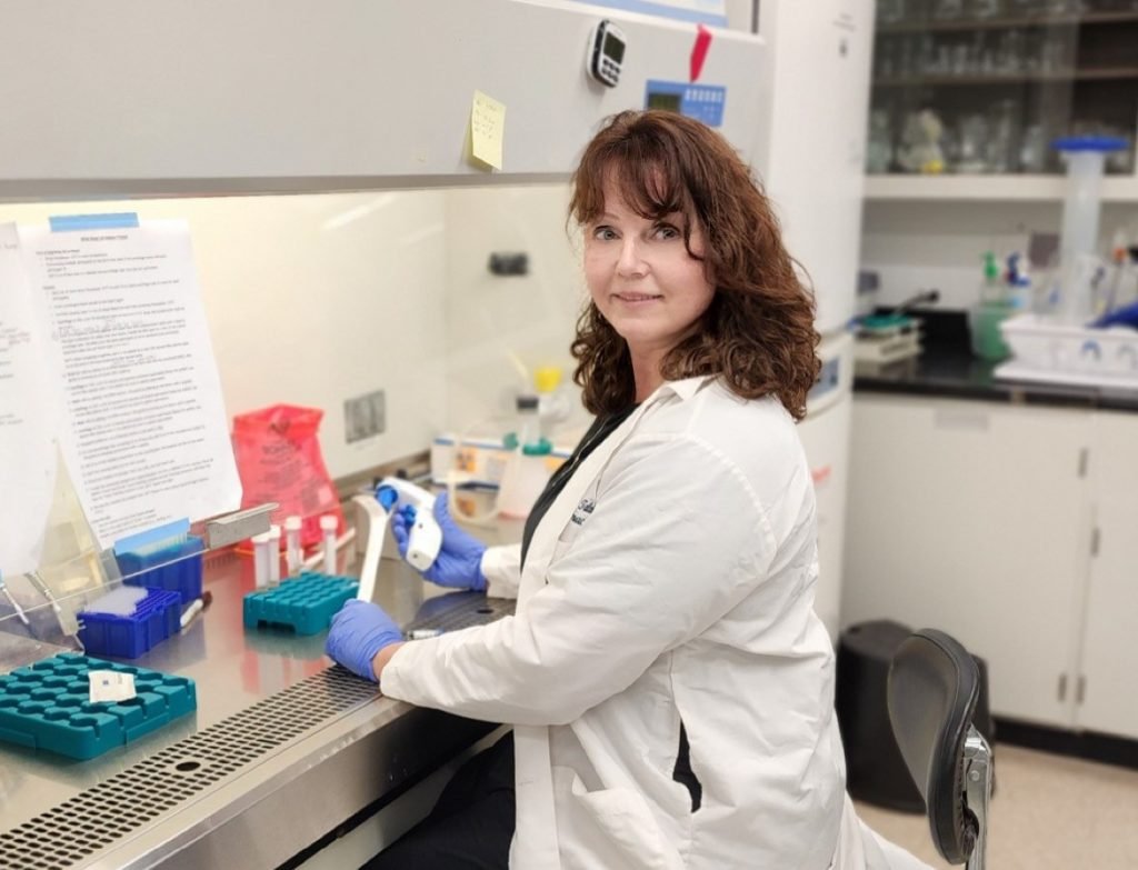 A woman, Susanne Talcott, in a lab coat sitting in her lab