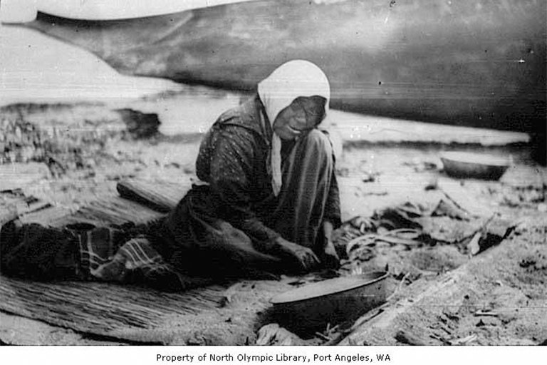 A Native American woman wrapping her share of whale meat in a mat at Neah Bay, U.S.