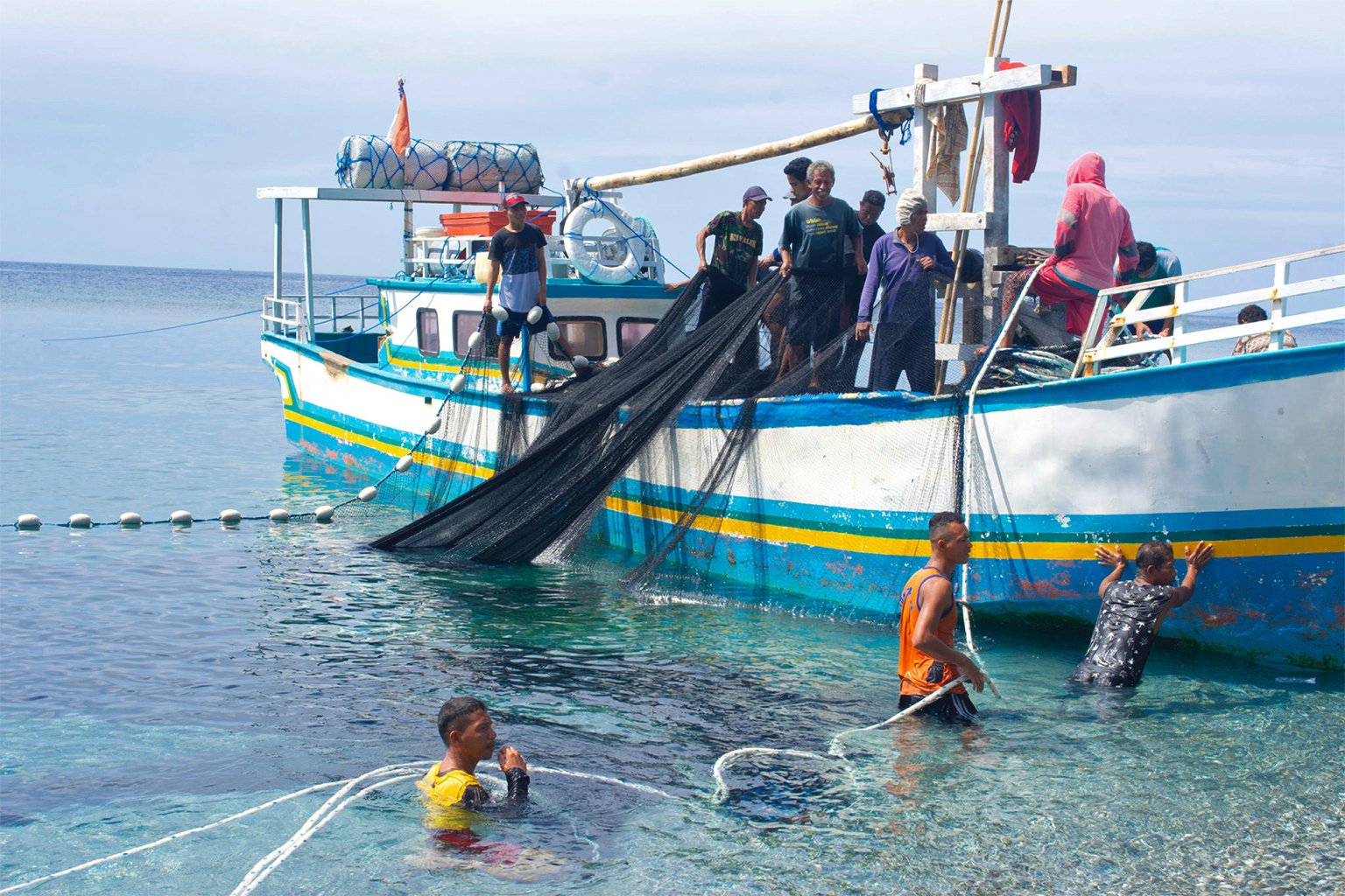 A group of Moluccan fishermen clean their fishing nets after using them in the sea. 