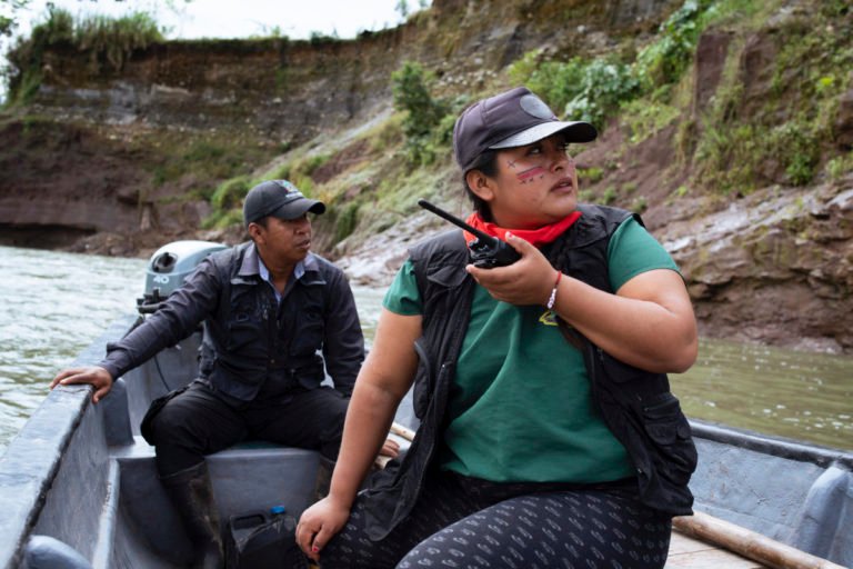 Alexandra Narváez and Holger Quenamá travel on the Aguarico River in a boat belonging to the Sinangoe Indigenous Guard.