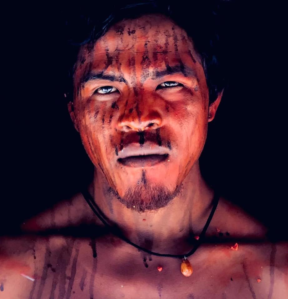 Indigenous Guajajara leader Paulo Paulino Guajajara, who was shot dead in an alleged ambush by loggers in the Brazilian Amazon. Following traditional rituals calling for protection, his face is painted with red dye from urucum seeds and black dye from shredded genipap fruit. Image courtesy of Patrick Raynaud/Mídia Índia.