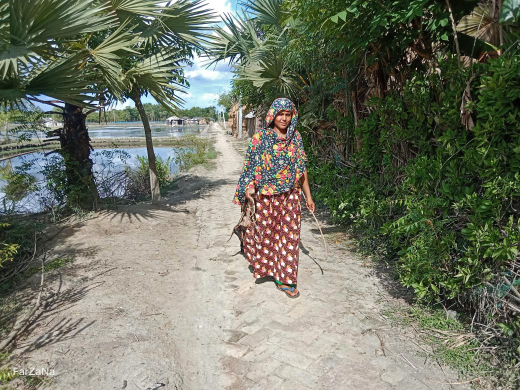 A woman walks with her goat