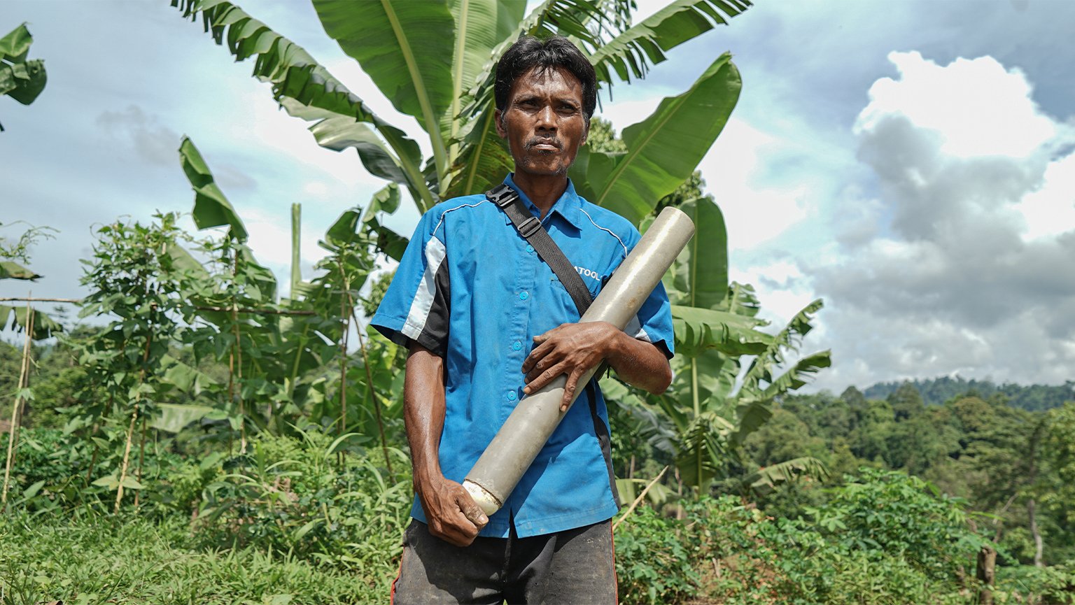 Junaidi, 42, poses with his PVC cannon in front of his farm in Alue Buloh.