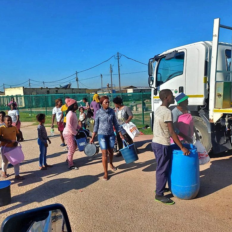 Residents queue up at trucks to collect their daily water ration.