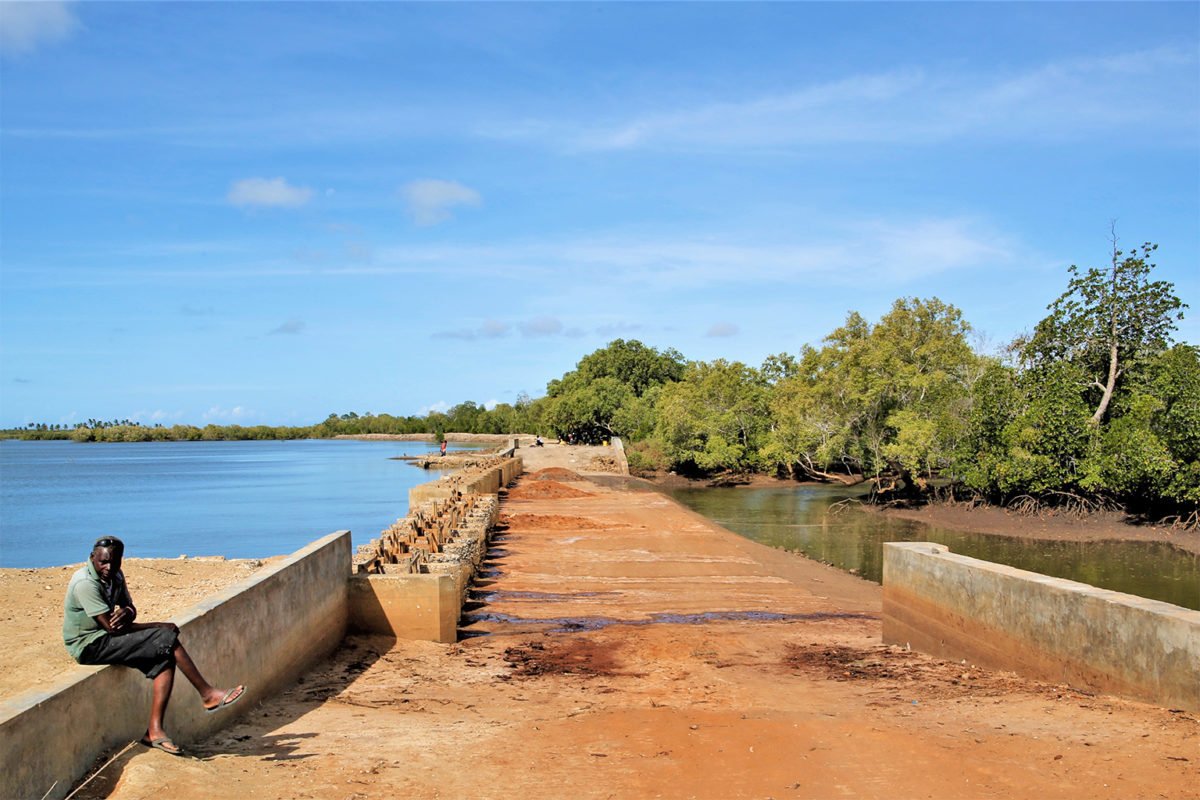 A man sits near a water inlet for Malindi Salt Works.