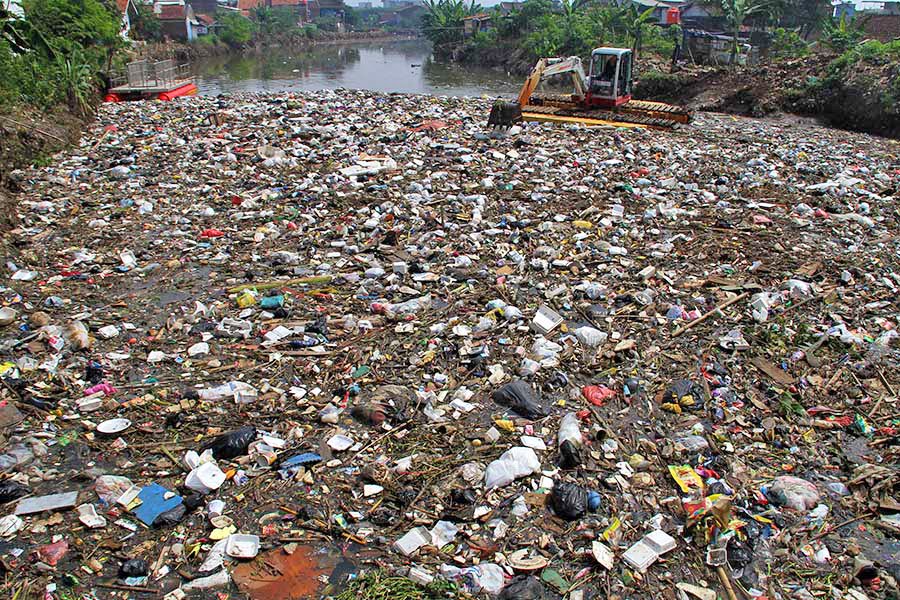 A backhoe grapples with garbage in the Cikapundung River