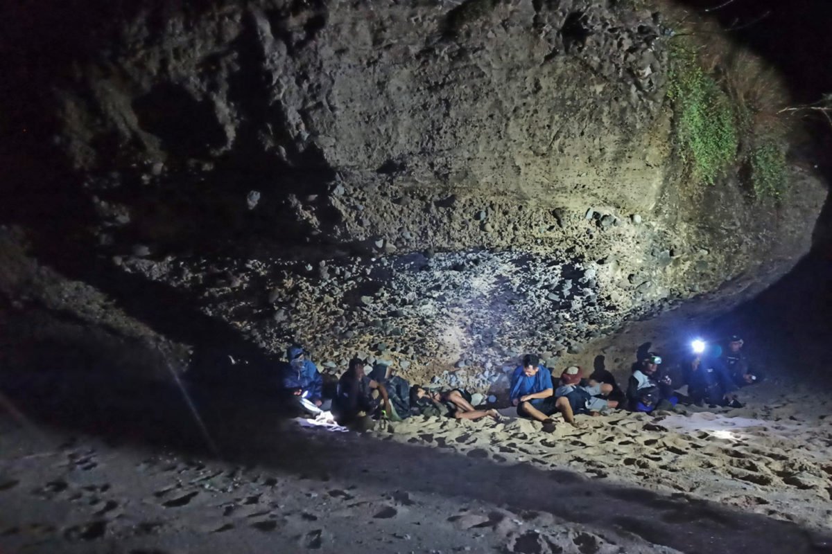 Turtle egg hunters take shelter from a light rain under a cliff on Mawil Beach in West Sumbawa.