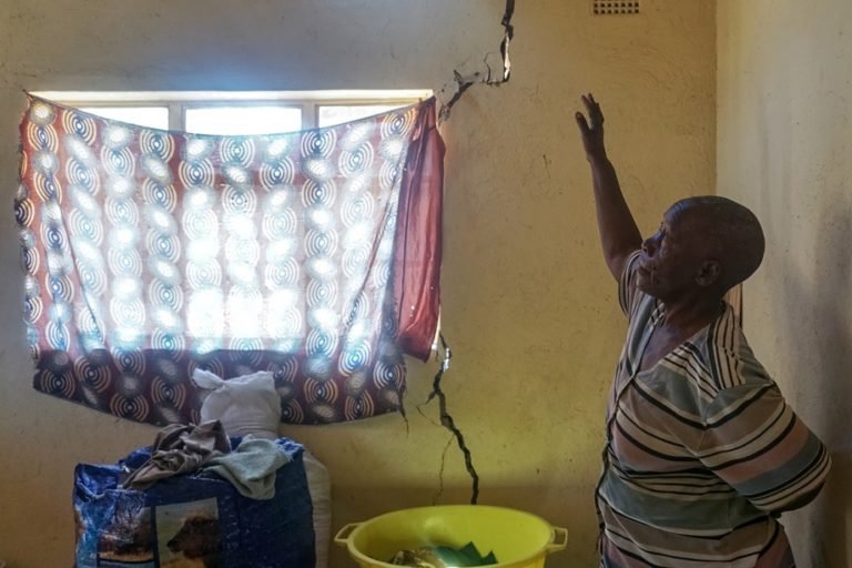 Alice Gama looks at cracks that have developed on the wall of her house in Arda Transau. Image courtesy of Linda Mujuru, GPJ Zimbabwe.